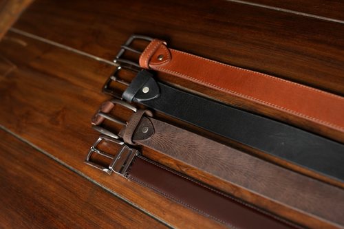 Four Stagr belts laid on walnut