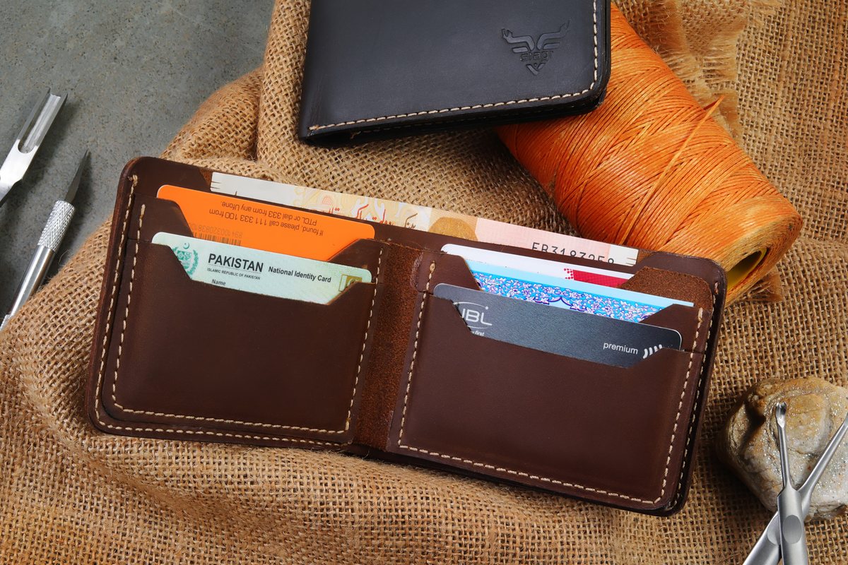 An open Stagr bifold holding cards, beside thread and tools on burlap